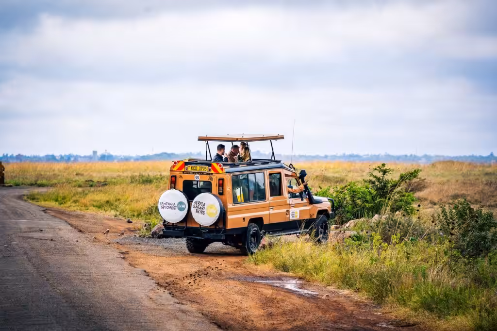 Safarijeep med resenärer som spanar ut genom det öppna taket vid en väg i den afrikanska bushen.