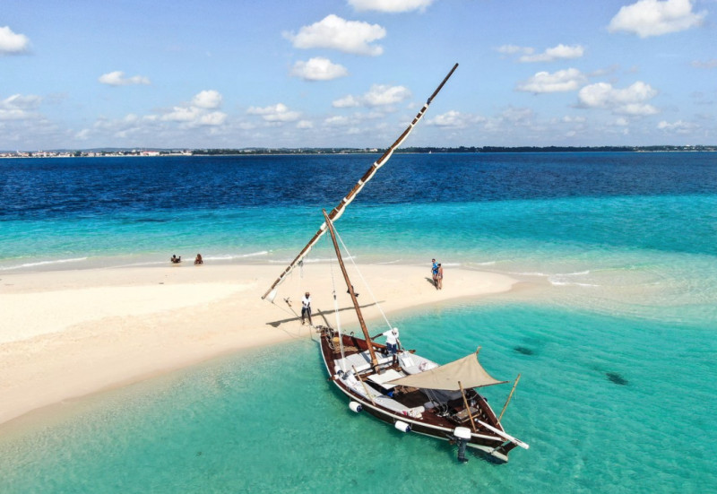 En båt vid en sanddyna i Zanzibar, omgiven av turkost vatten.