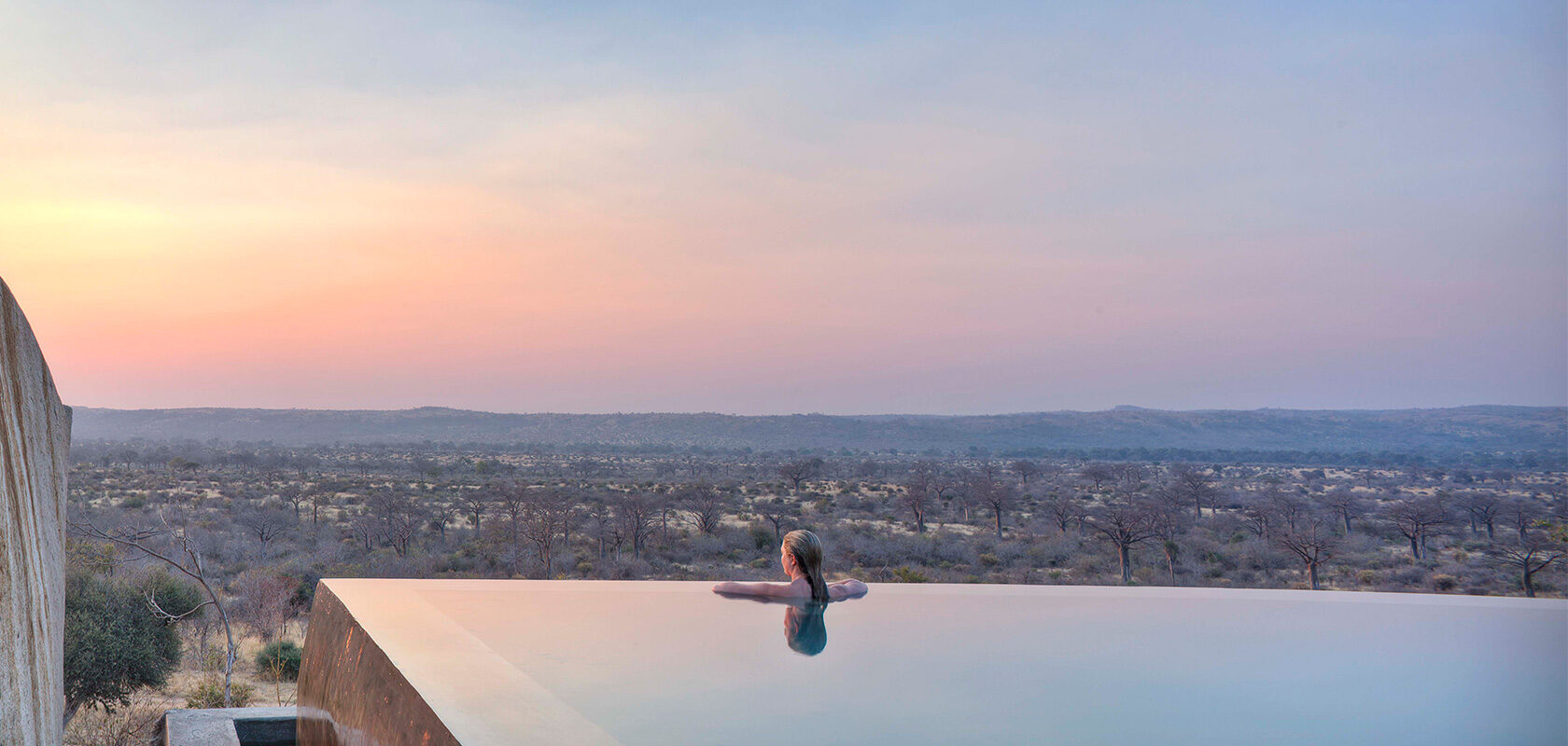 En kvinna på kanten av en infinity pool på Jabali Ridge lyxresort i Tanzania