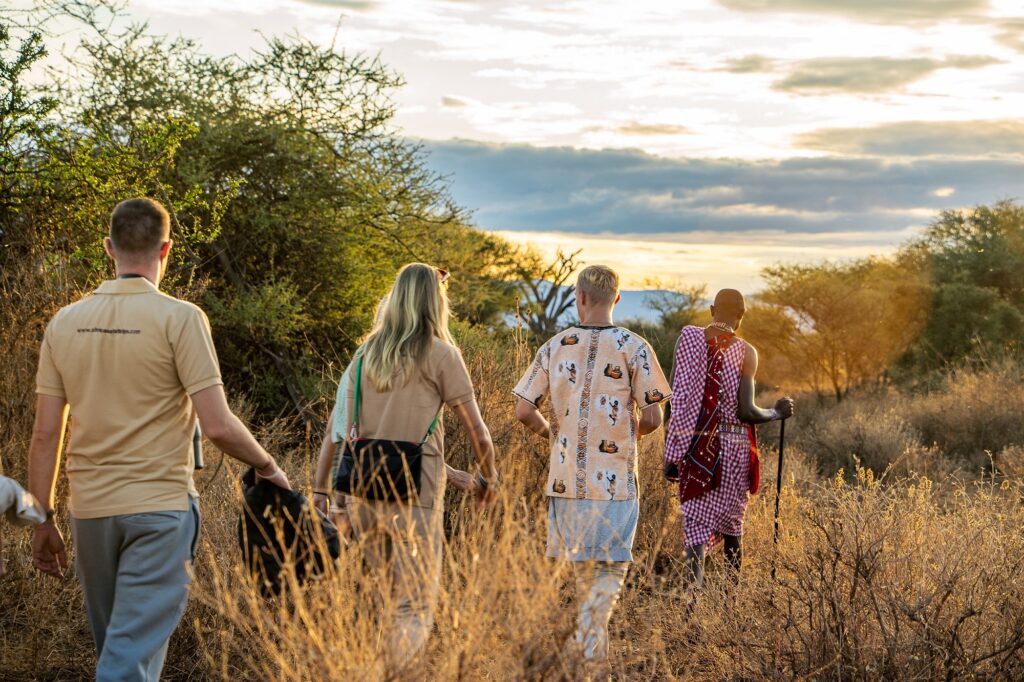 Gäster i savannen på en vandrande safari med en massaj