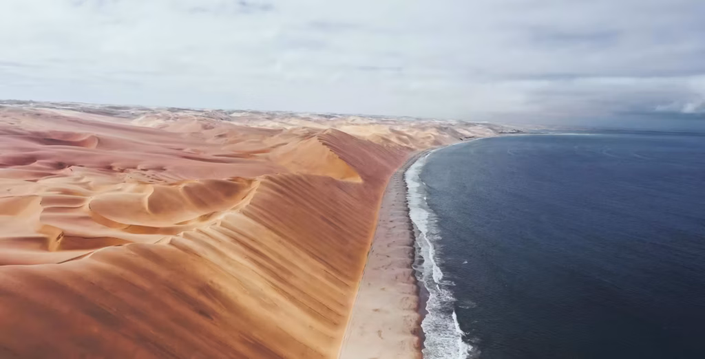 Sandwich Harbour i Namibia sett uppifrån, med höga sanddyner till vänster, en strand i mitten och havet till höger